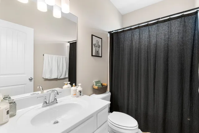 a bathroom with a sink a toilet a mirror and shower curtain