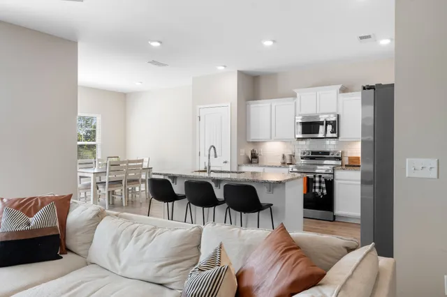 a living room with stainless steel appliances kitchen island granite countertop a couch and cabinets