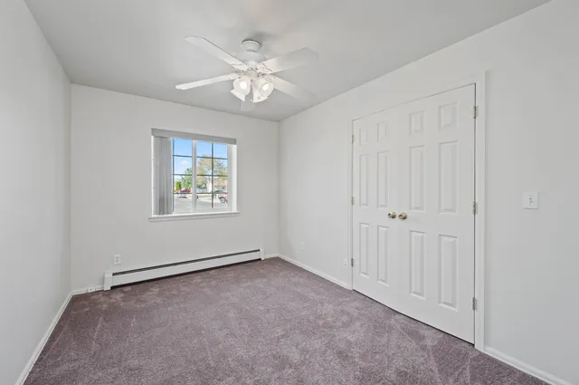 an empty room with windows and fan