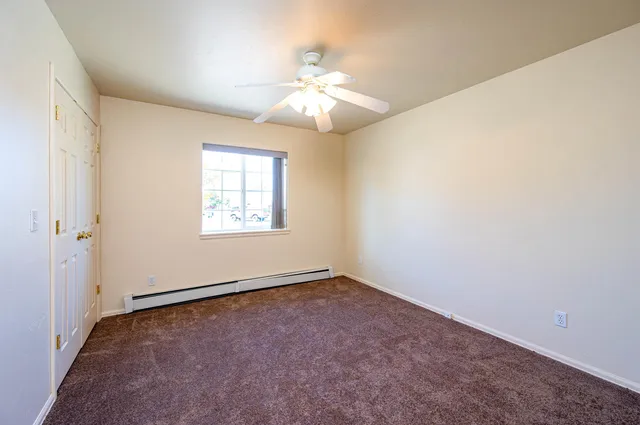 an empty room with windows and fan
