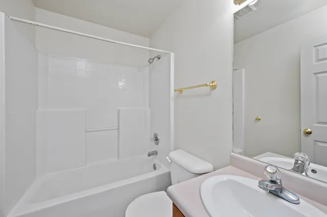a bathroom with a bathtub shower sink vanity and toilet