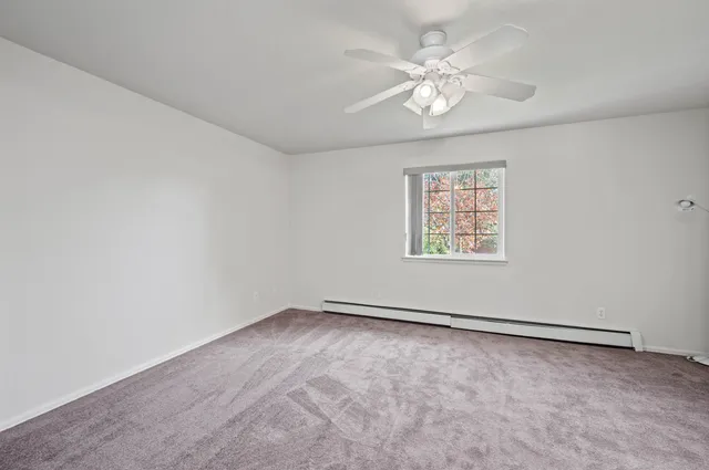 an empty room with windows and chandelier fan