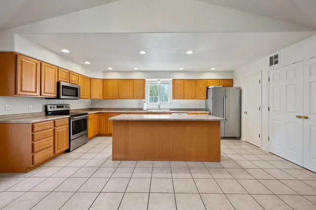 a large kitchen with stainless steel appliances granite countertop a refrigerator and a stove top oven