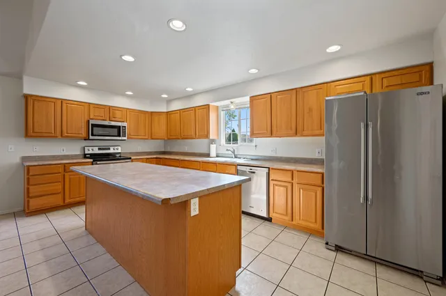 a kitchen with stainless steel appliances granite countertop a refrigerator and a stove top oven