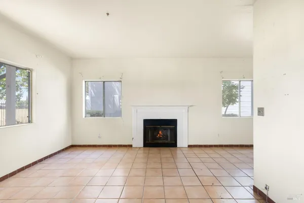 an empty room with windows and fireplace