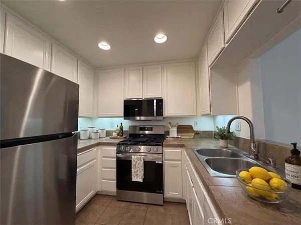 a kitchen with stainless steel appliances a refrigerator sink and white cabinets