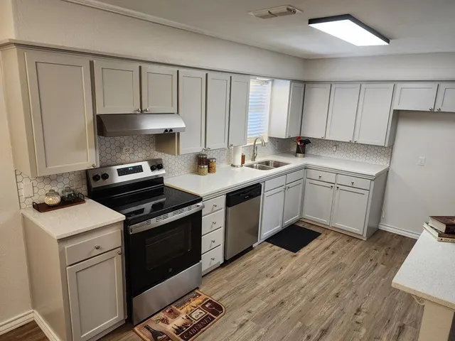 a kitchen with a stove sink and cabinets