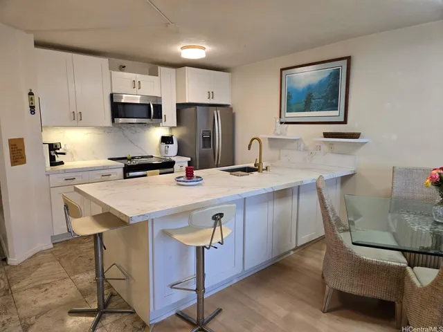 a kitchen with stainless steel appliances granite countertop a sink a stove a refrigerator cabinets and chairs