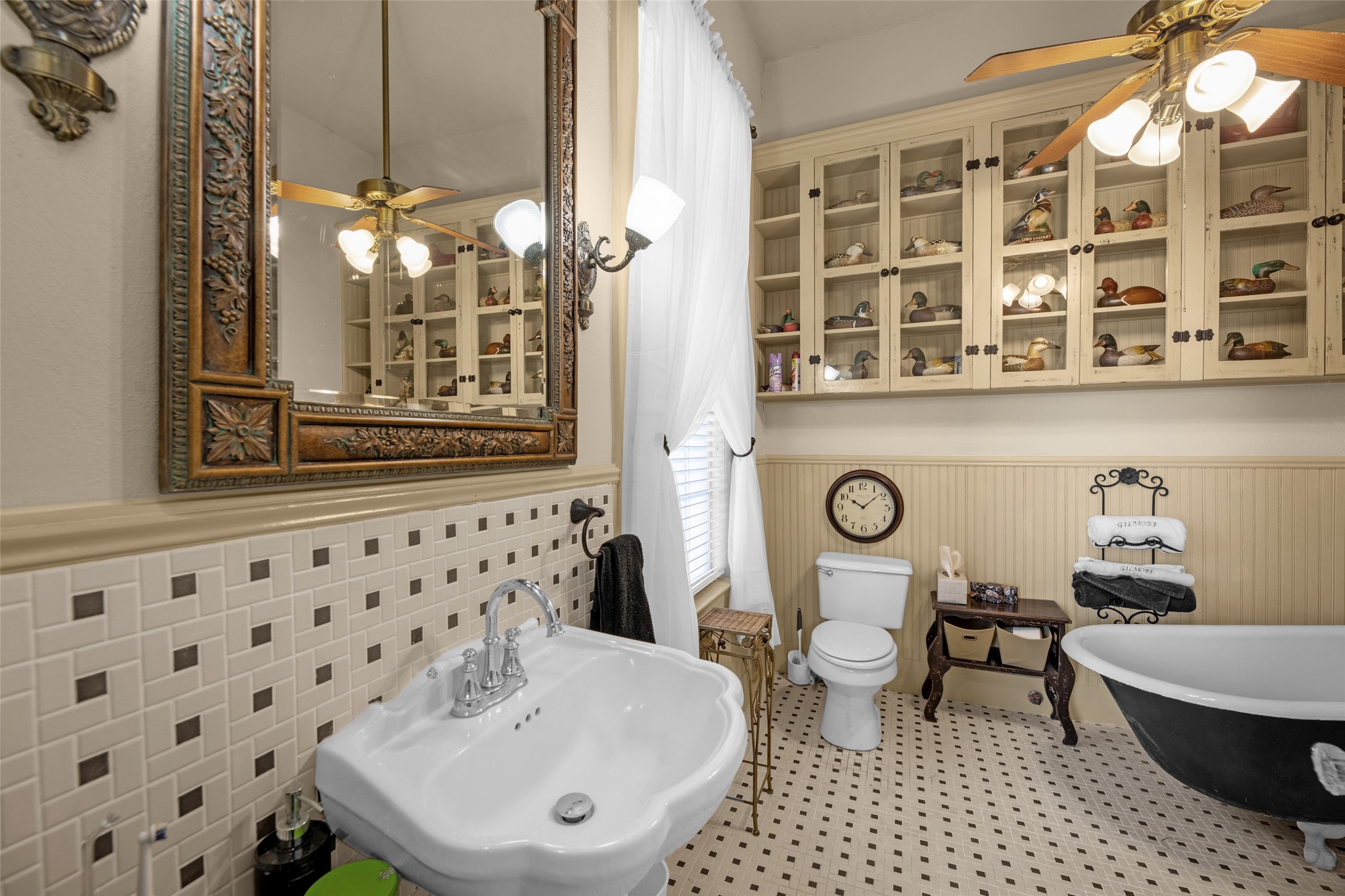 801 North Fulton Street Wharton, TX 77488 - Photo 21 of 43 Here's another view of the primary bath with a black clawfoot tub, mosaic tile floor, pedestal sink, and built-in glass-front display cabinets