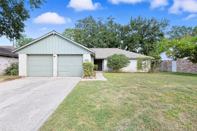 a view of a house with a yard and large tree