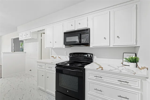a kitchen with stainless steel appliances granite countertop white cabinets and a stove