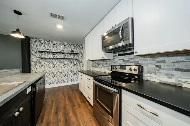 a kitchen with stainless steel appliances a stove sink microwave and cabinets