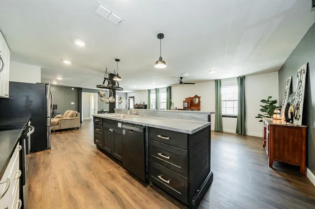 a kitchen with stainless steel appliances granite countertop a sink a stove and a wooden floors