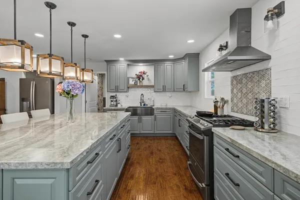 a kitchen with stainless steel appliances granite countertop a sink a stove and a wooden floors