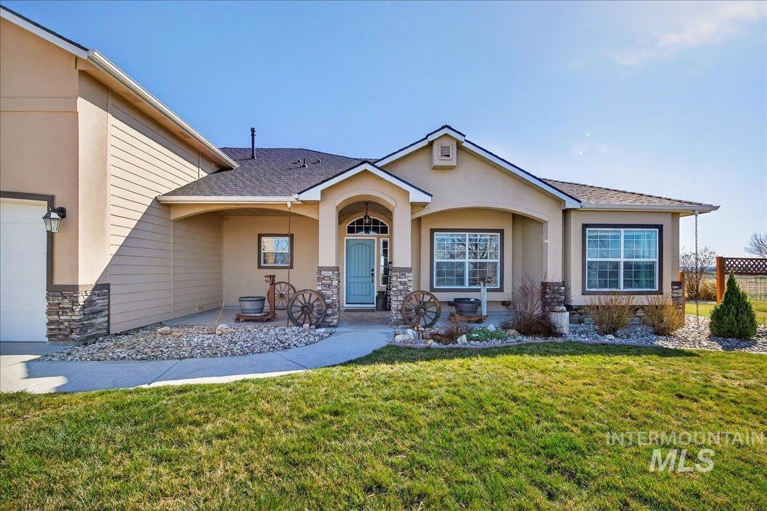 View of front of property with stone siding, stucco siding, a front yard, and roof with shingles