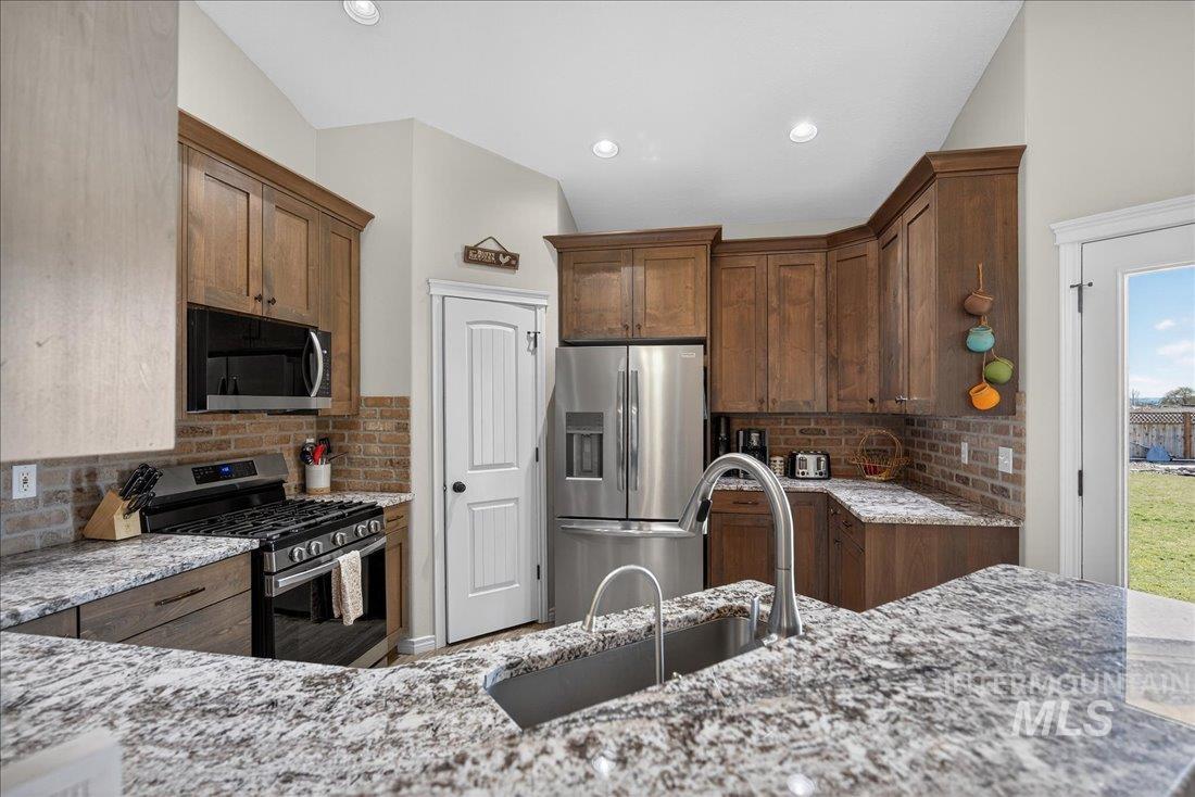 5408 Cassia Road New Plymouth, ID 83655 - Photo 12 of 49 Kitchen featuring stainless steel appliances, light stone counters, decorative backsplash, and recessed lighting