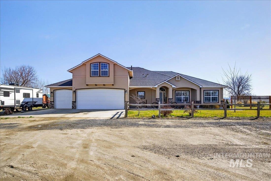 5408 Cassia Road New Plymouth, ID 83655 - Photo 2 of 49 View of front facade featuring concrete driveway, stucco siding, a fenced front yard, and stone siding