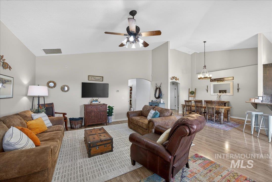 5408 Cassia Road New Plymouth, ID 83655 - Photo 5 of 49 Living area with light wood-style flooring, a ceiling fan, arched walkways, lofted ceiling, and suspended lighting