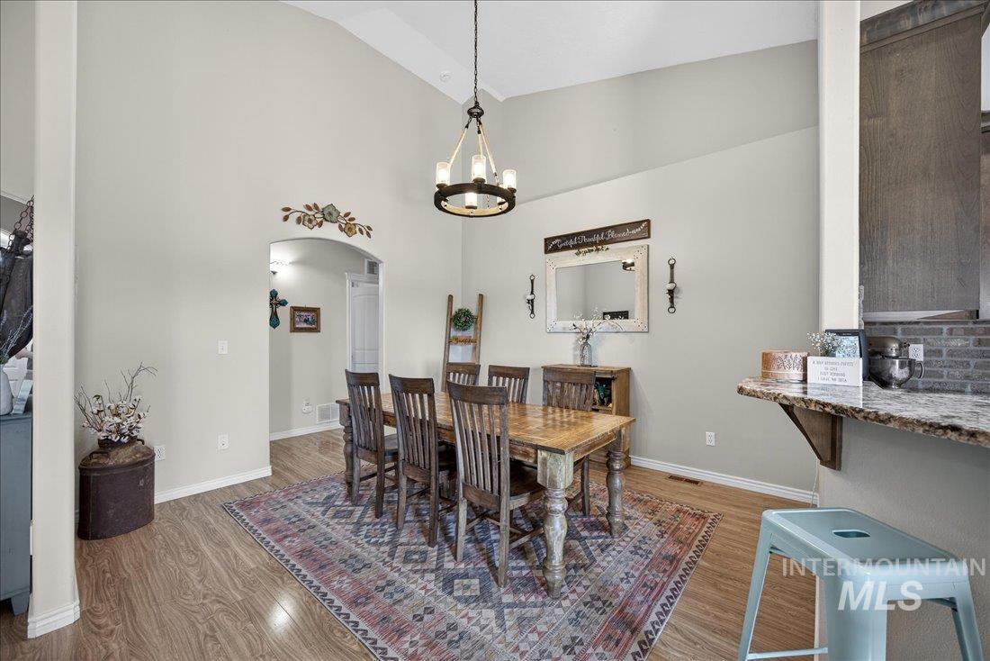 5408 Cassia Road New Plymouth, ID 83655 - Photo 8 of 49 Dining area featuring arched walkways, wood finished floors, lofted ceiling, and a chandelier