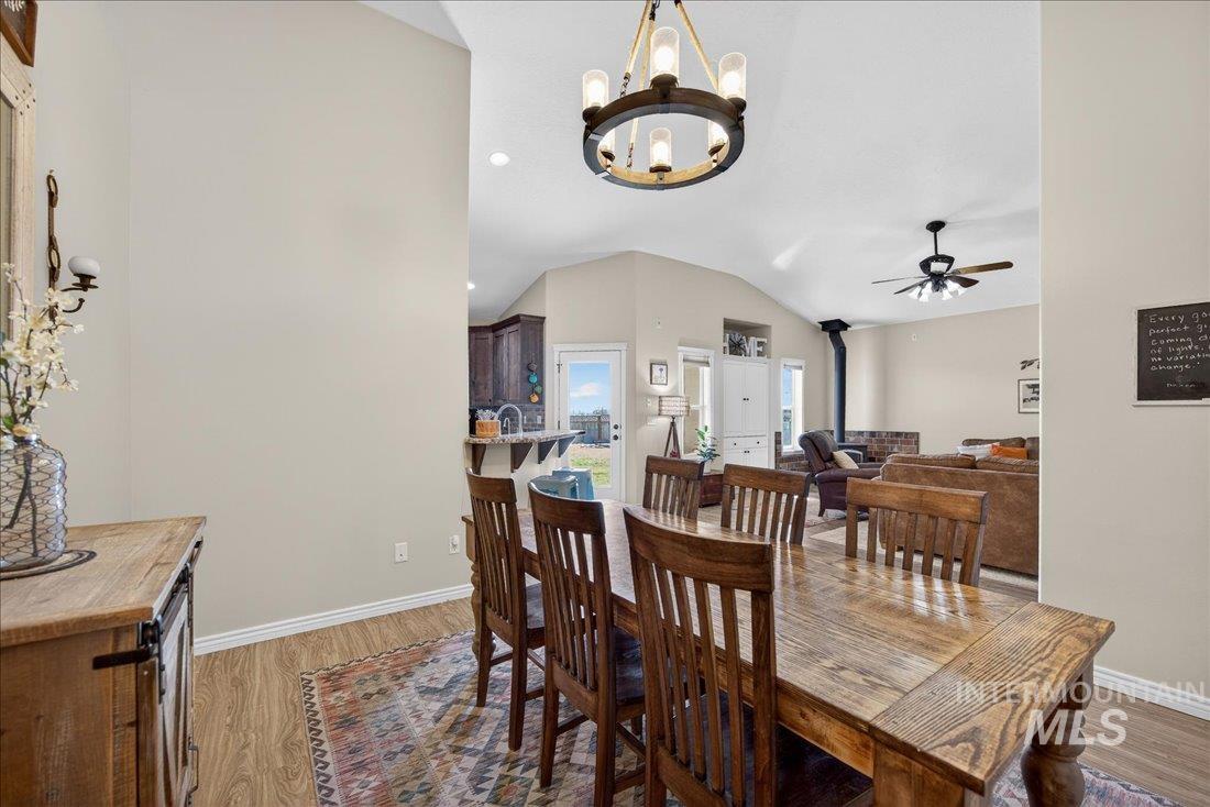 5408 Cassia Road New Plymouth, ID 83655 - Photo 10 of 49 Dining space featuring hanging lights, a wood stove, vaulted ceiling, light wood-style flooring, and ceiling fan