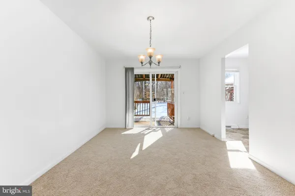 an empty room with chandelier fan and windows