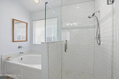 a bathroom with a bath tub a window and a shower