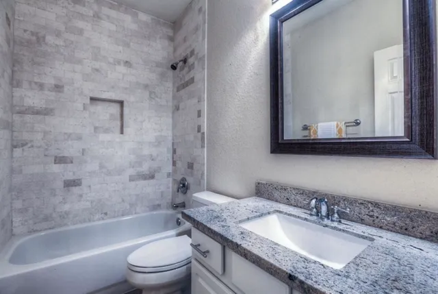 a bathroom with a granite countertop sink toilet and shower