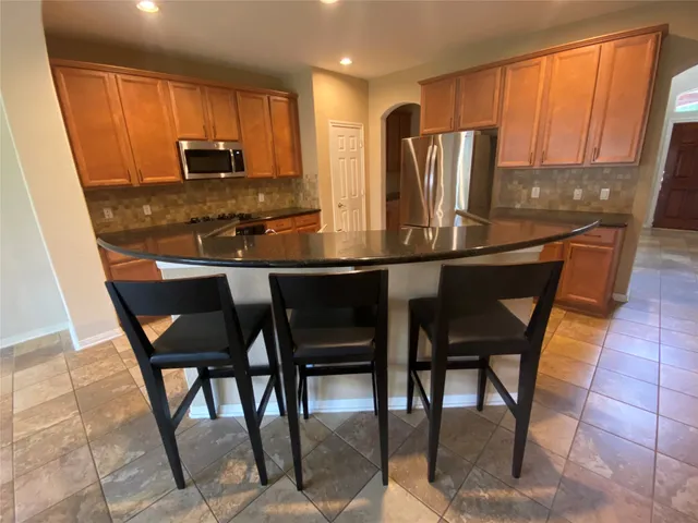 a kitchen with stainless steel appliances granite countertop table chairs sink and microwave