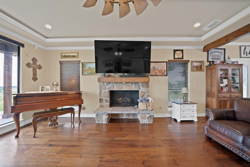 100 Shadle Ridge Court Poolville, TX 76487 - Photo 4 of 40 Living area featuring wood-finish flooring, a stone-clad fireplace with a wood mantel, recessed lighting, and crown molding