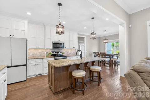 a kitchen with center island stainless steel appliances and wooden floor