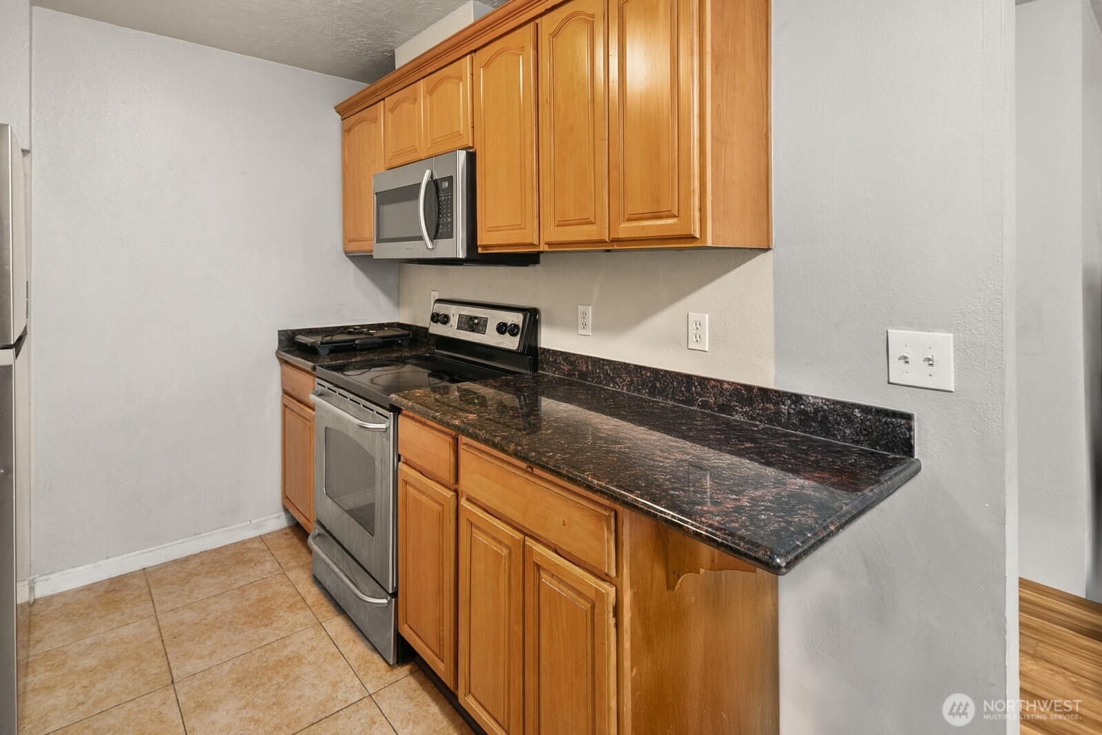 101 Southwest 119th Street, Unit 102 Burien, WA 98146 - Photo 11 of 15 a kitchen with stainless steel appliances granite countertop a stove a sink and a microwave