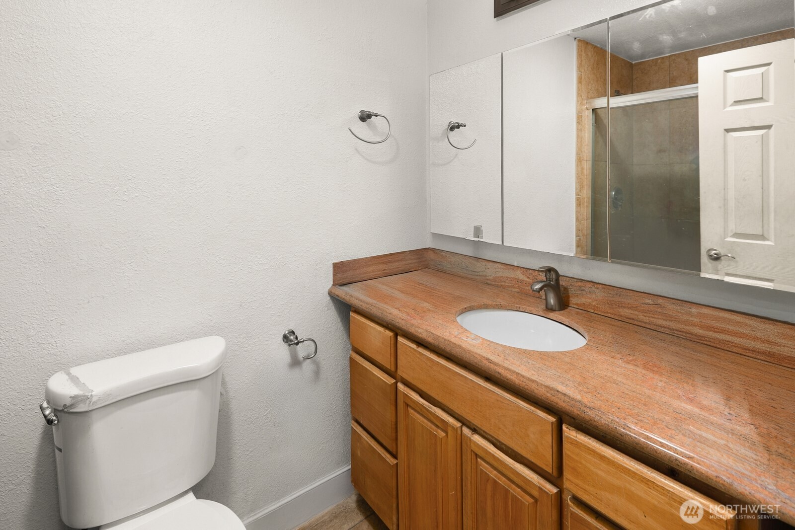 101 Southwest 119th Street, Unit 102 Burien, WA 98146 - Photo 15 of 15 a bathroom with a granite countertop toilet sink and mirror
