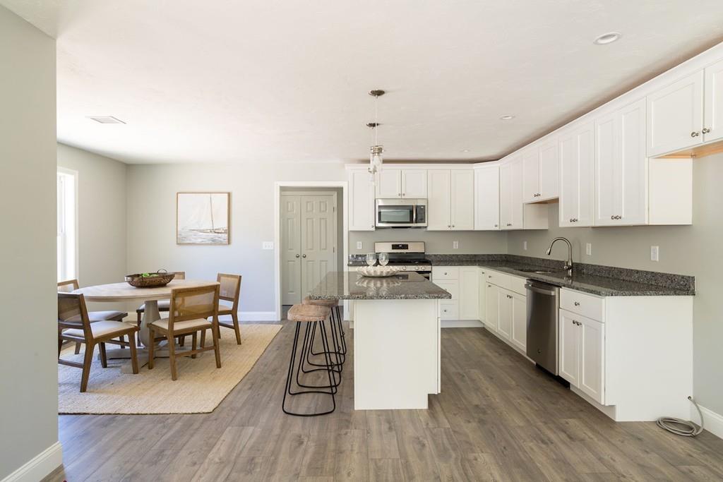 11 Indian Neck Road Wareham, MA 02571 - Photo 23 of 41 a kitchen with stainless steel appliances kitchen island granite countertop wooden floors and white cabinets