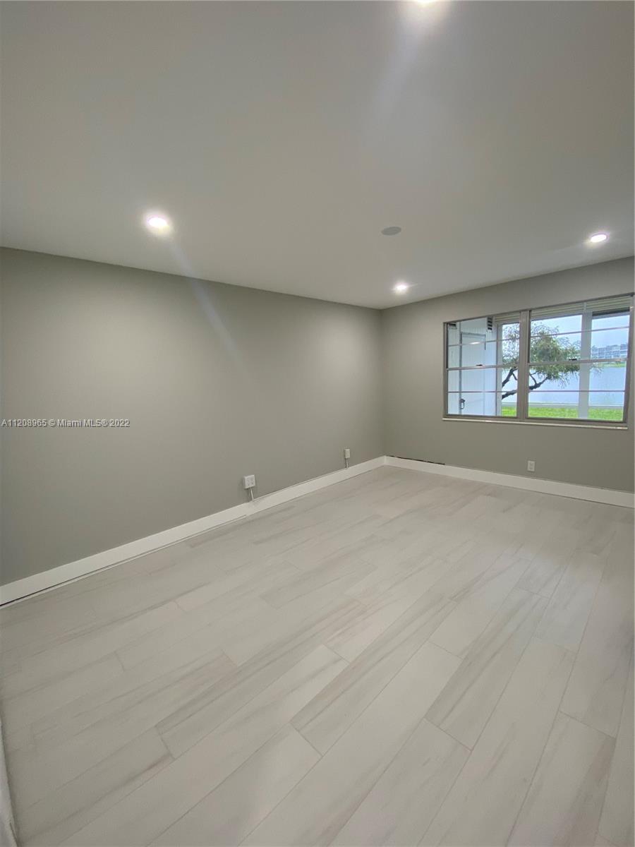 1058 Guildford East, Unit 1058 Boca Raton, FL 33434 - Photo 8 of 14 an empty room with wooden floor and windows
