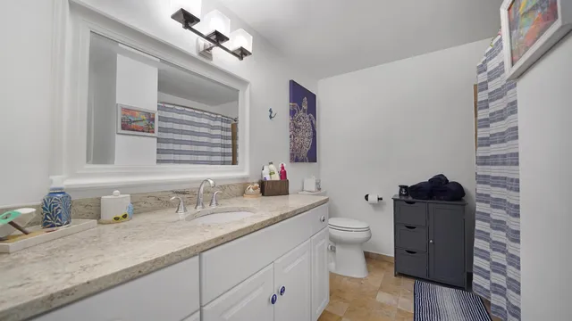 a bathroom with a granite countertop toilet sink and mirror