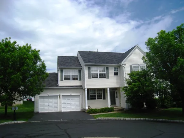 a front view of a house with a garden and trees