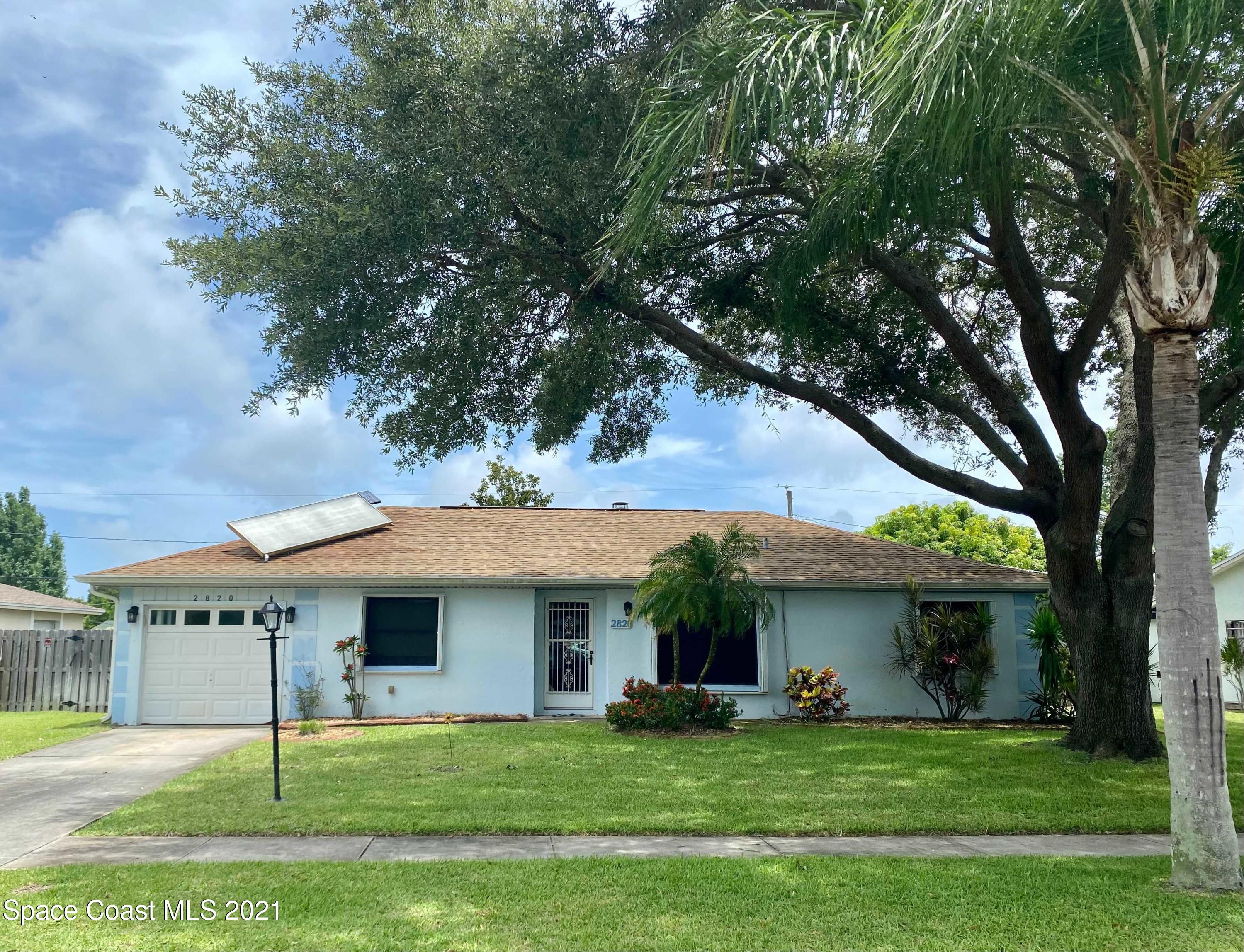 2820 Locksley Road Melbourne, FL 32935 - Photo 3 of 6 a view of a house with a yard and a large tree