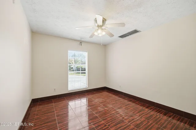 an empty room with windows and fan
