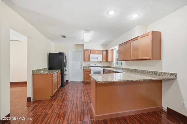 a kitchen with stainless steel appliances granite countertop wooden cabinets a sink and dishwasher a stove with wooden floor