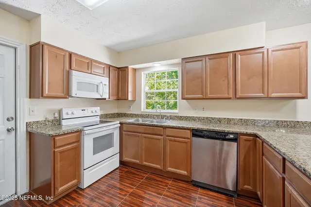 a kitchen with stainless steel appliances granite countertop a refrigerator and a sink