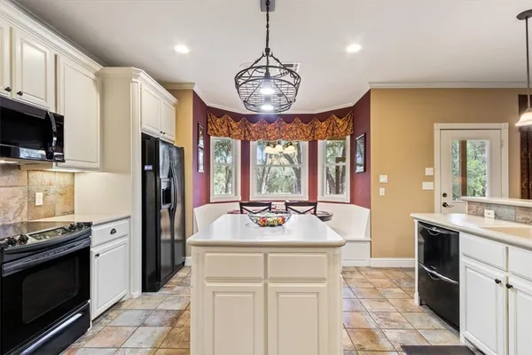 a kitchen with a sink and dishwasher with white cabinets