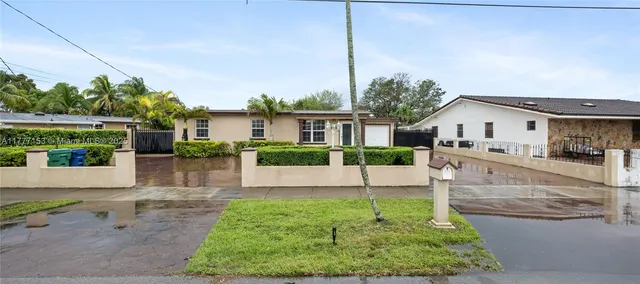 a view of a white house next to a yard with potted plants