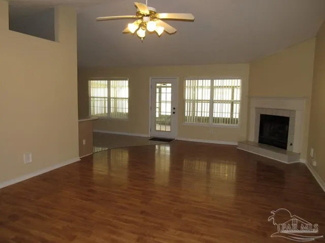 a view of empty room with wooden floor and fan