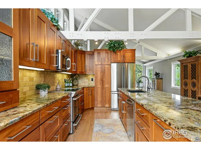 a kitchen with stainless steel appliances granite countertop a sink a stove and a wooden floors