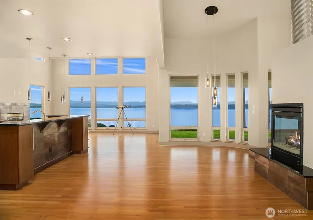 a view of a living room with floor to ceiling window and kitchen view