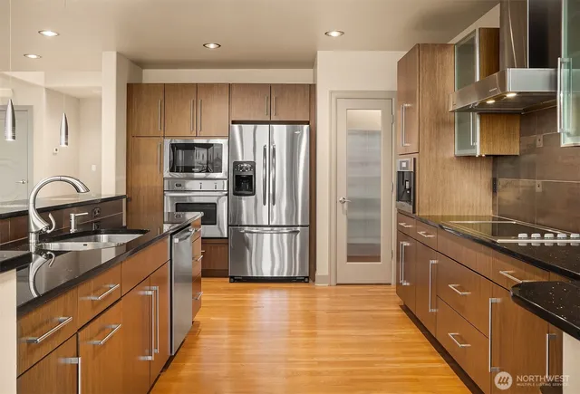 a kitchen with stainless steel appliances granite countertop a refrigerator a sink a stove and oven