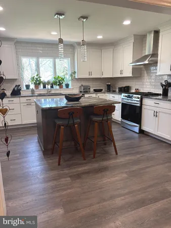 a kitchen with stainless steel appliances granite countertop a table chairs sink and cabinets