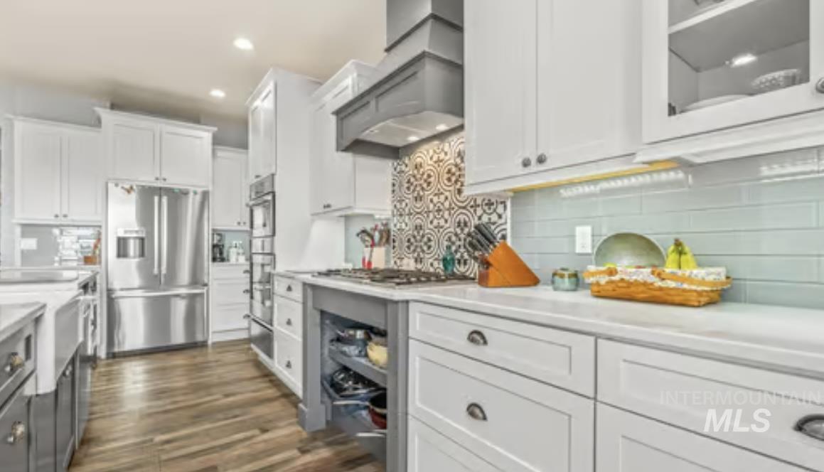 16353 Brunello Court Caldwell, ID 83607 - Photo 12 of 45 Kitchen with white cabinets, appliances with stainless steel finishes, dark wood finished floors, backsplash, and recessed lighting