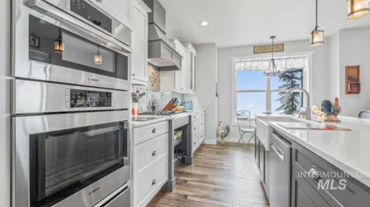 16353 Brunello Court Caldwell, ID 83607 - Photo 14 of 45 Kitchen featuring stainless steel appliances, light countertops, white cabinetry, decorative light fixtures, and gray cabinets