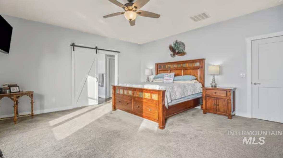 16353 Brunello Court Caldwell, ID 83607 - Photo 18 of 34 Bedroom featuring a barn door, a ceiling fan, and light carpet